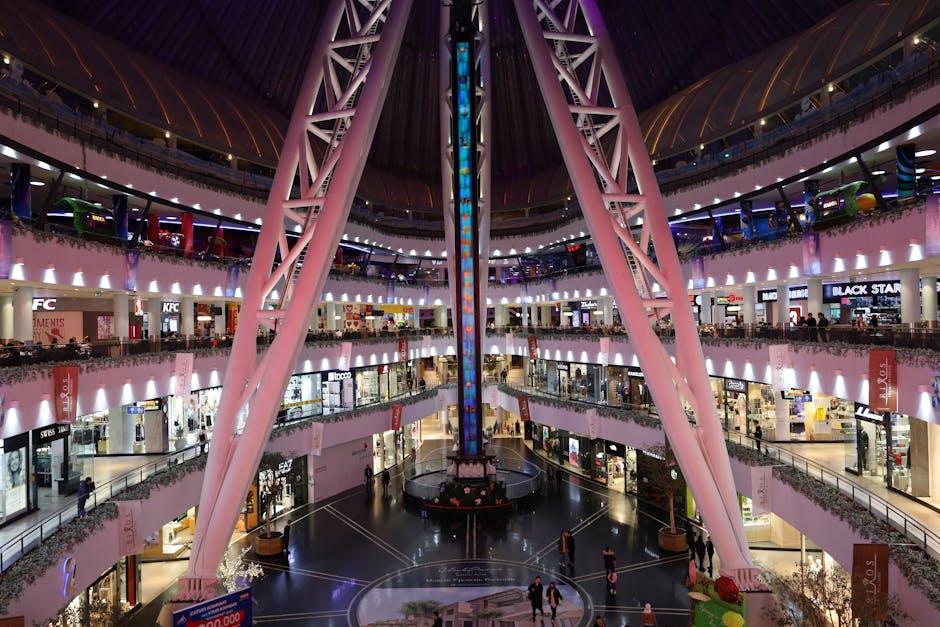 A vibrant and spacious modern shopping mall with various shops and people bustling around.