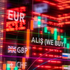 Dynamic forex trading concept with currency symbols and candlestick chart illuminated on screen.