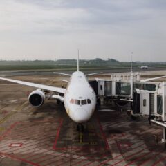 A modern jet airplane docked at an airport terminal gate, ready for boarding on a cloudy day.