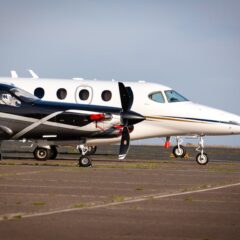 Luxury private aircraft parked on an airport tarmac, ready for departure under clear blue skies.