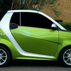 Side view of a green smart car parked on a street in Shefford, showcasing its modern design and alloy rims.