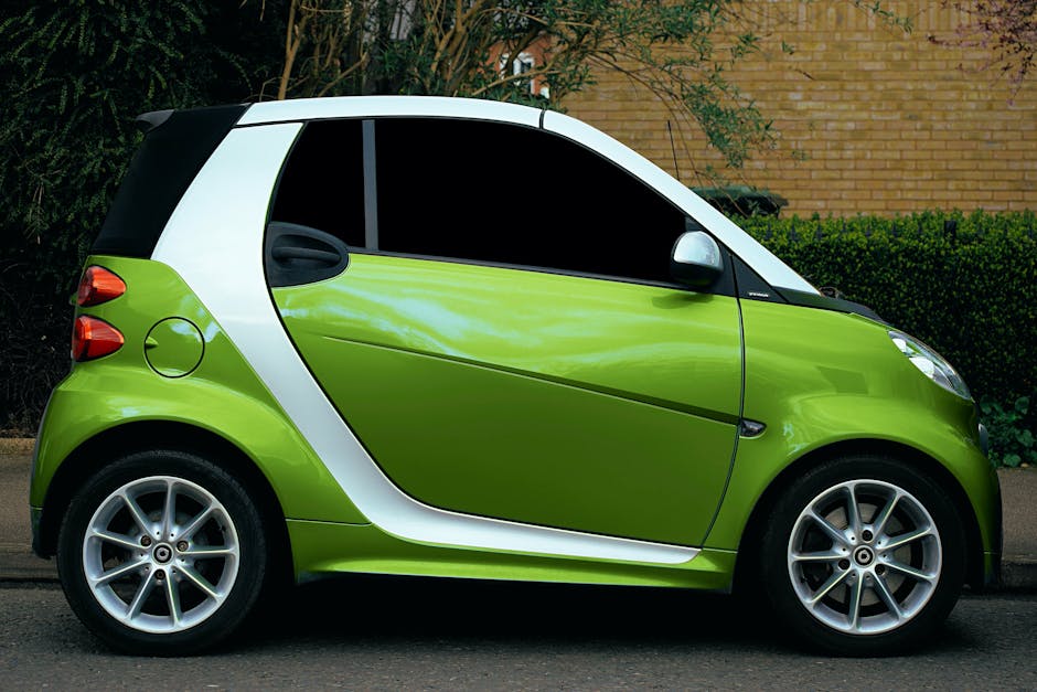 Side view of a green smart car parked on a street in Shefford, showcasing its modern design and alloy rims.