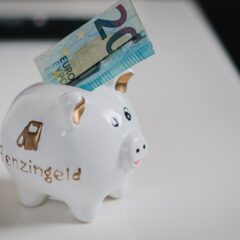 A white piggy bank with a €20 note inserted, symbolizing savings.