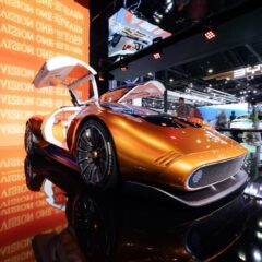 A sleek futuristic concept car in vivid orange displayed at an international motor show.
