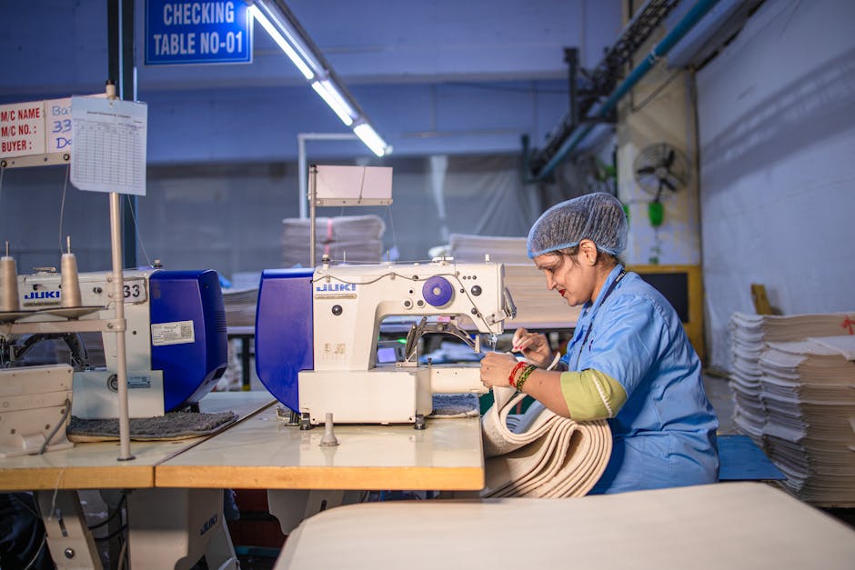A woman operating a sewing machine in a textile factory, focused and skilled.
