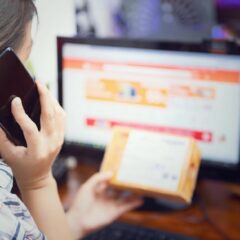 Woman multitasking by using a phone and checking an online purchase package at home.