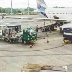 Ground support services in action at an airport terminal with visible aircraft and service vehicles.