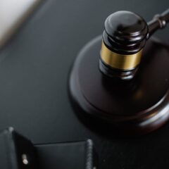 From above of wooden gavel on round surface near folders on table in courtroom