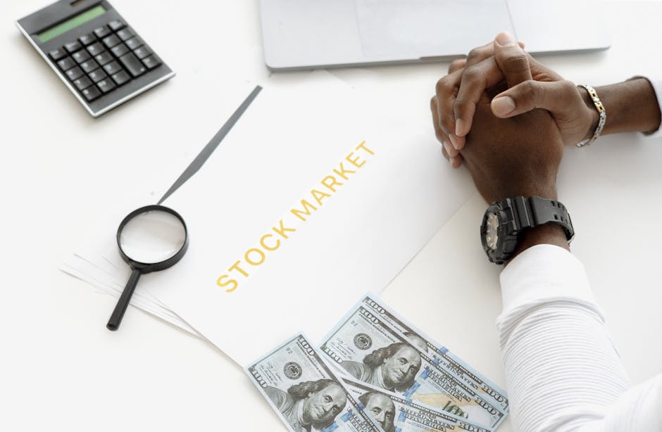 Hands folded over stock market documents with calculator and cash on desk.