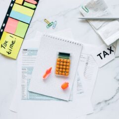 Flat lay of tax preparation essentials with calculator, forms, and colorful sticky notes.