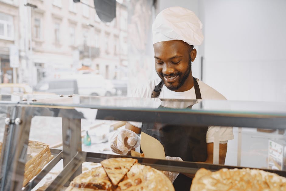 A cheerful baker in an apron serves pastries in a bright bakery display.
