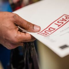 A close-up of a hand holding a document with a 'Past Due' stamp, highlighting financial urgency.