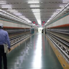 Long hallway in a textile factory with a worker walking, showcasing industrial machinery.