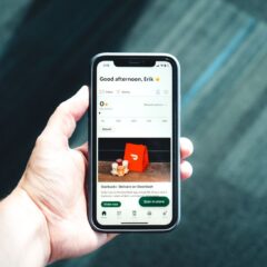 Close-up of a smartphone with a delivery app interface in a person's hand, emphasizing modern e-commerce.