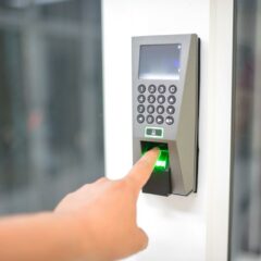 A person uses a fingerprint scanner for secure entry in a business setting.