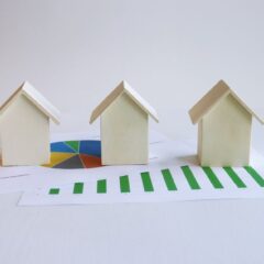 Wooden model houses on graphs depict real estate market analysis and trends.
