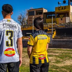 Two sports fans wearing team jerseys at the CAP stadium on a sunny day.