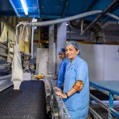 Female workers in a textile factory managing fabric production machines indoors.