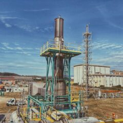 View of an industrial plant with metal structures and buildings under a clear blue sky in Crotone, Calabria, Italy.