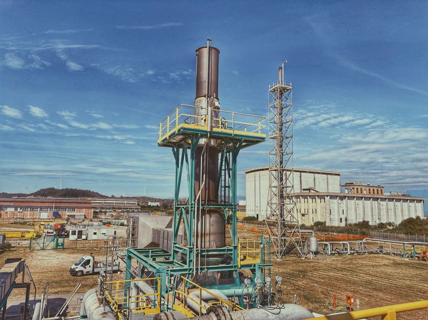 View of an industrial plant with metal structures and buildings under a clear blue sky in Crotone, Calabria, Italy.