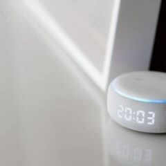 Close-up of a smart speaker with a digital clock display on a minimalist surface.