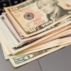 Stack of US dollar bills on a keyboard, symbolizing digital finance and wealth.