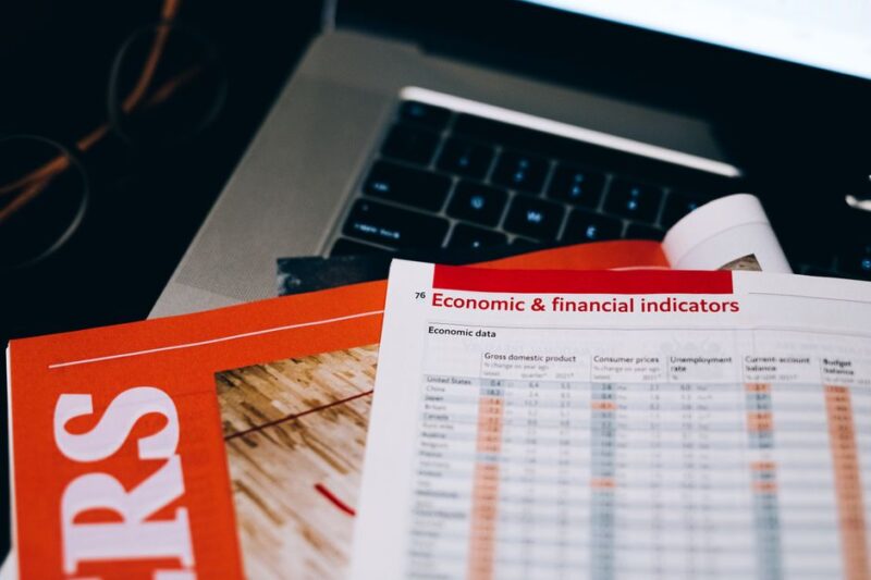 Detailed close-up of economic and financial documents on a laptop keyboard, highlighting data analytics.