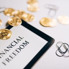 Close-up of Bitcoin coins and an iPad displaying 'Financial Freedom,' symbolizing modern digital savings.
