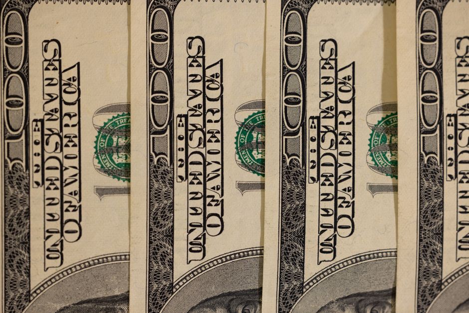 Detailed close-up of multiple US hundred dollar bills, showcasing currency design.
