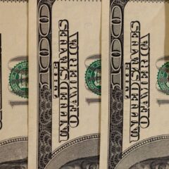 Detailed close-up of multiple US hundred dollar bills, showcasing currency design.