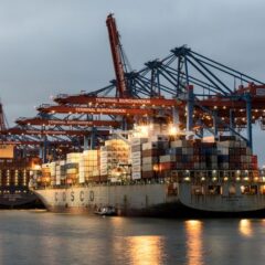 Container ships docked at Hamburg's Burchardkai Terminal during twilight, showcasing bustling maritime activity.