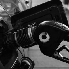 Detailed close-up of a refueling nozzle in monochrome at a gas station, highlighting the petrol filling process.