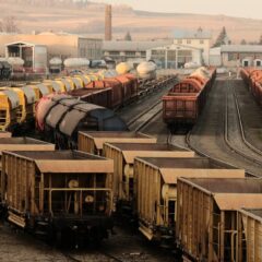 A busy freight train yard with multiple tracks and a variety of train cars in a rural setting.