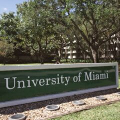 Outdoor view of the University of Miami entrance with lush greenery during the day.