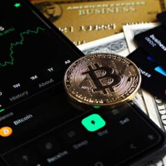 Bitcoin coin with financial data, credit cards, and currency on a desk.