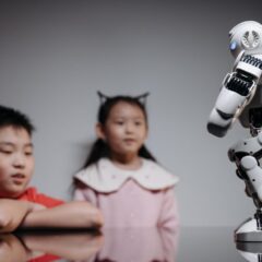 Two children watching and interacting with an innovative robot toy indoors.