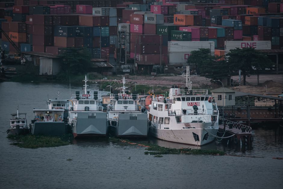 Ships docked at a bustling harbor with colorful cargo containers in view.