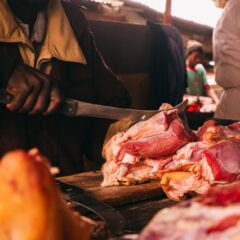 A butcher skillfully cuts meat in a lively market in Jos, Nigeria.