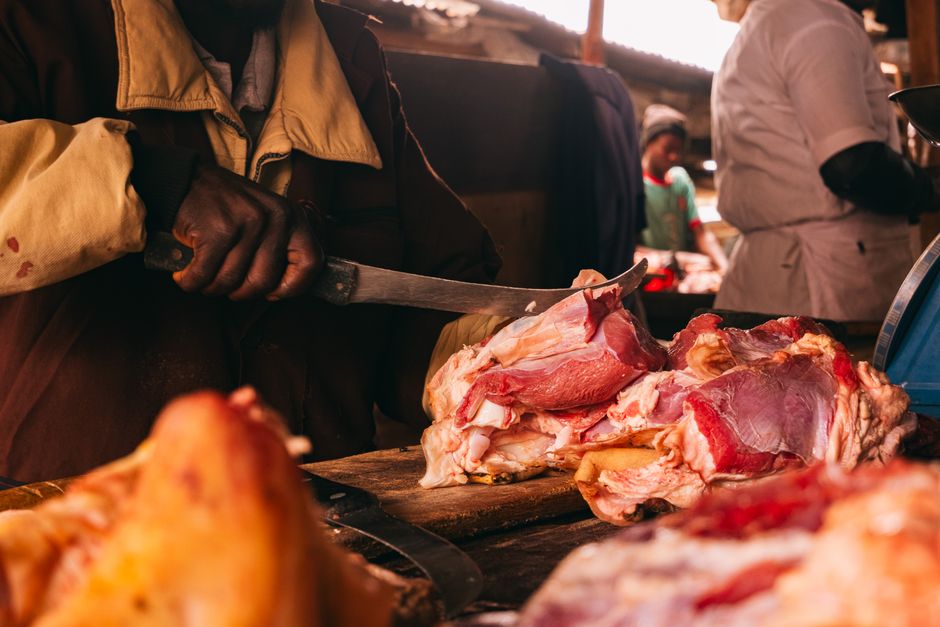 A butcher skillfully cuts meat in a lively market in Jos, Nigeria.