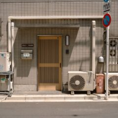 A minimalist facade with air conditioners and a no parking sign in Tokyo, Japan.
