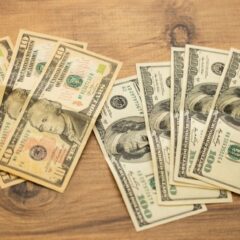 A collection of US dollar bills arranged on a wooden surface, showcasing currency denominations.