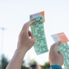 Close-up of hands holding transportation tickets, showcasing numbers and fare details.