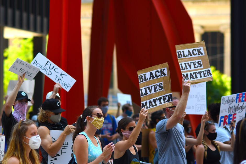 Protesters gather with signs supporting Black Lives Matter and denouncing Donald Trump in a peaceful rally.
