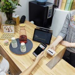 A woman makes a contactless payment at a stylish Berlin café, emphasizing technology and modern retail.