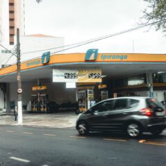 Ipiranga gas station with moving vehicles on a bustling city street.
