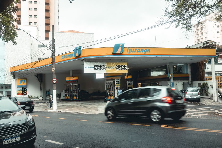 Ipiranga gas station with moving vehicles on a bustling city street.