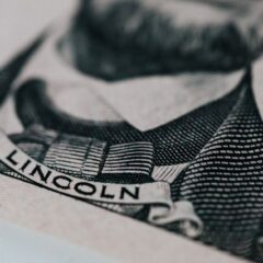 Crop of five dollar banknote with president Lincoln wearing costume on table