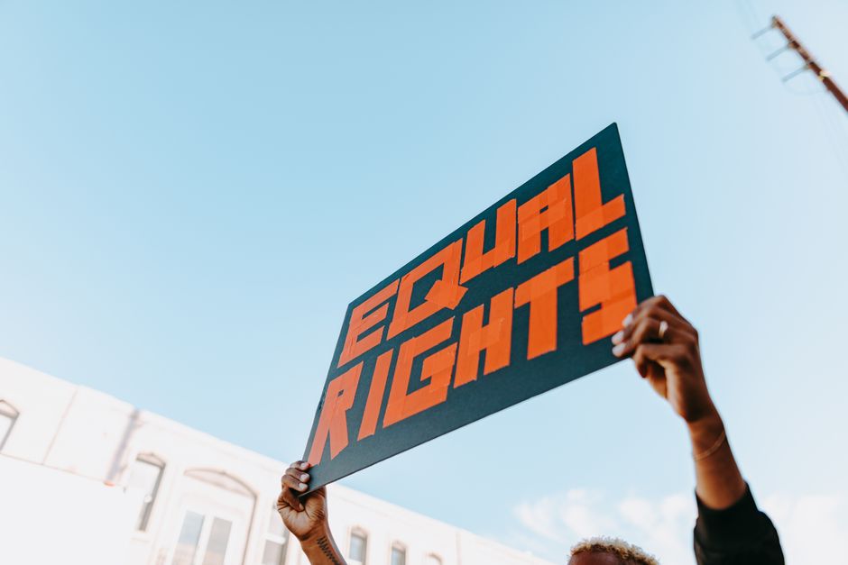 Hands holding a bold equal rights sign at an outdoor protest.