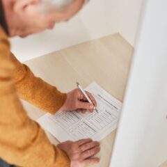 Senior man marking a ballot at a voting booth in an indoor polling station.
