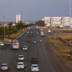 Aerial view of Brasília's urban traffic with prominent government buildings and a bustling road.